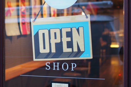 a sustainable sign that reads open placed outside the door of a business